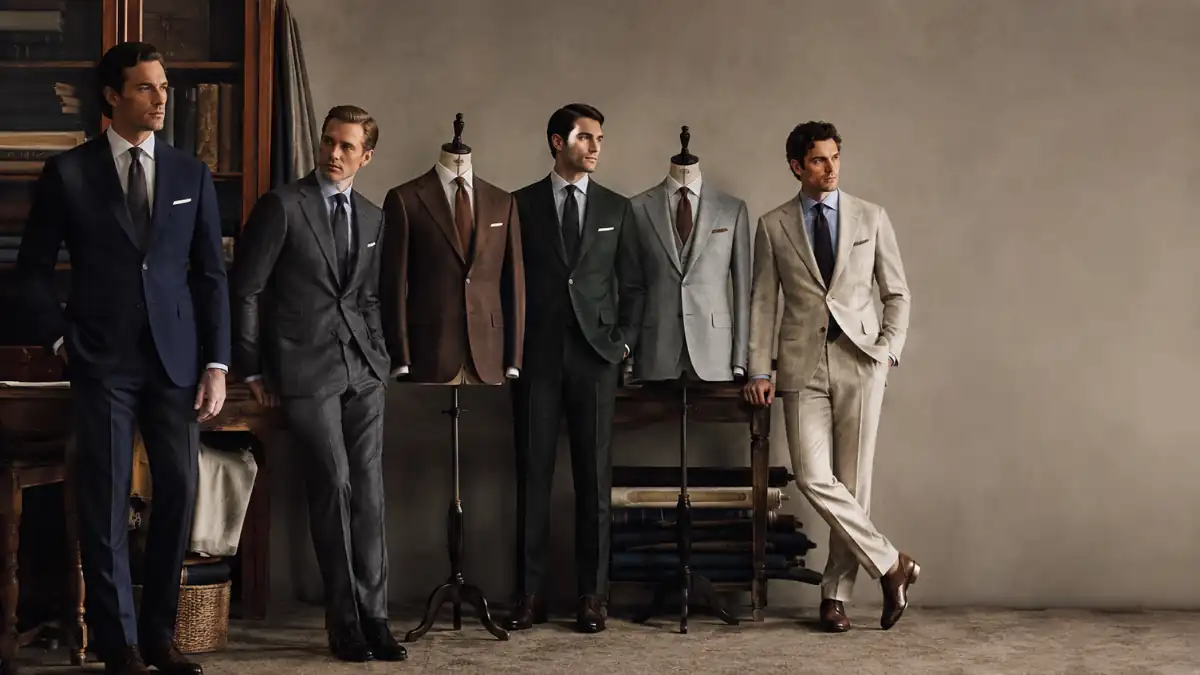 Best Suit Colours for Men featuring navy, charcoal grey, brown, dark green, light grey and beige tailored suits in a classic menswear setting